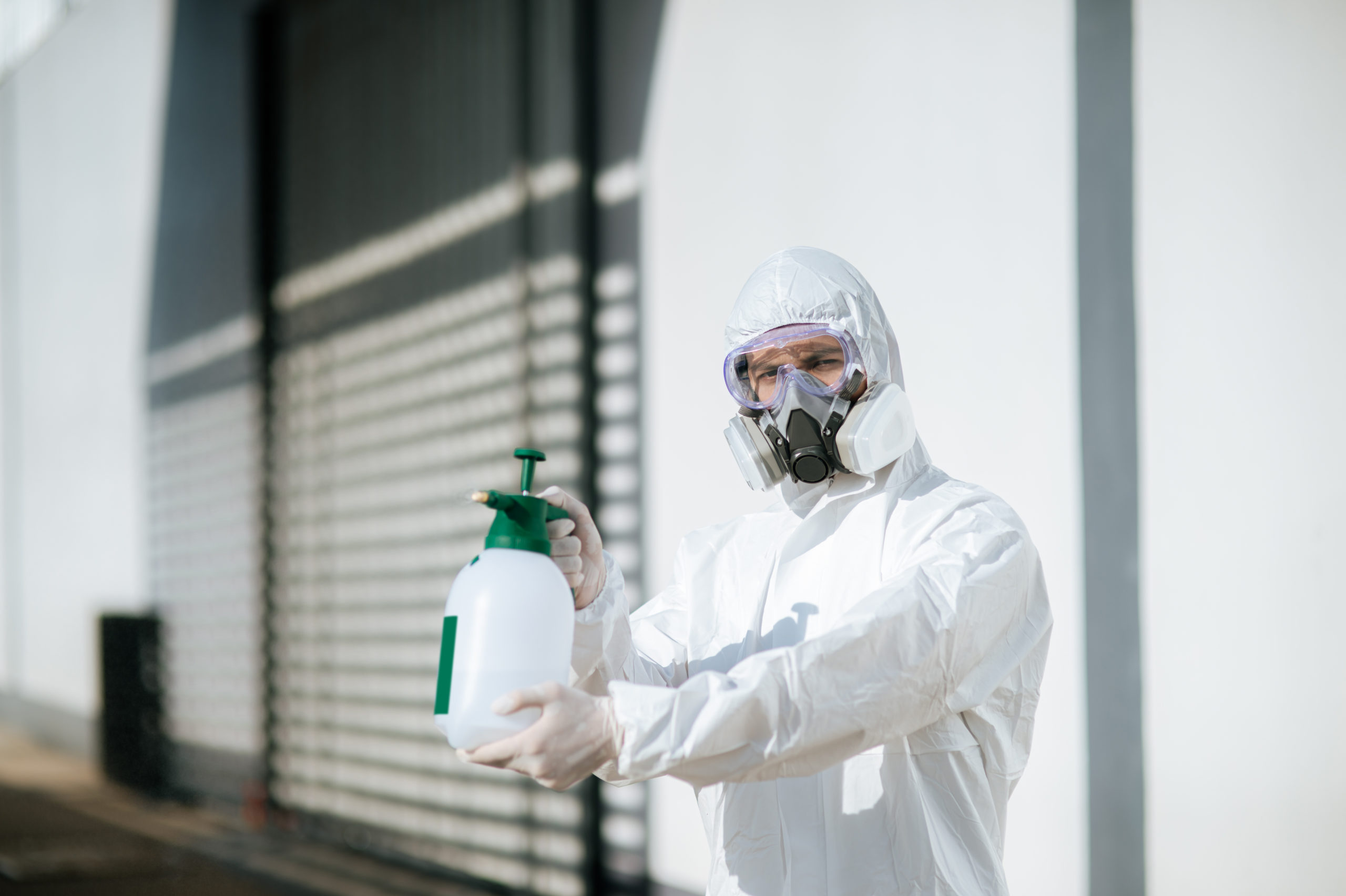 Disinfection specialist in PPE suit performing public decontamin
